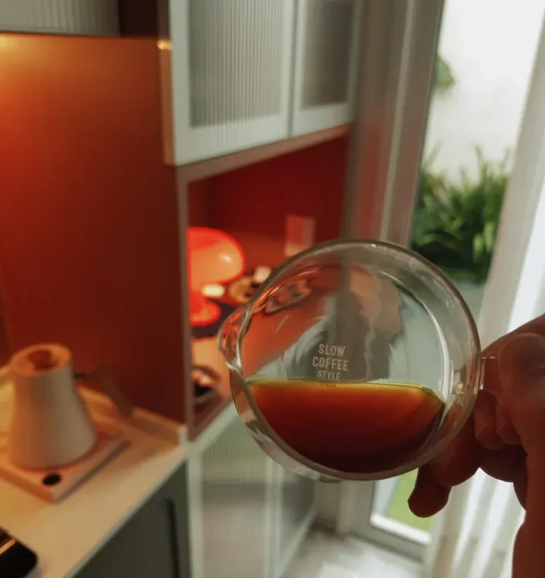 Café coado num copo de vidro, na cozinha de casa