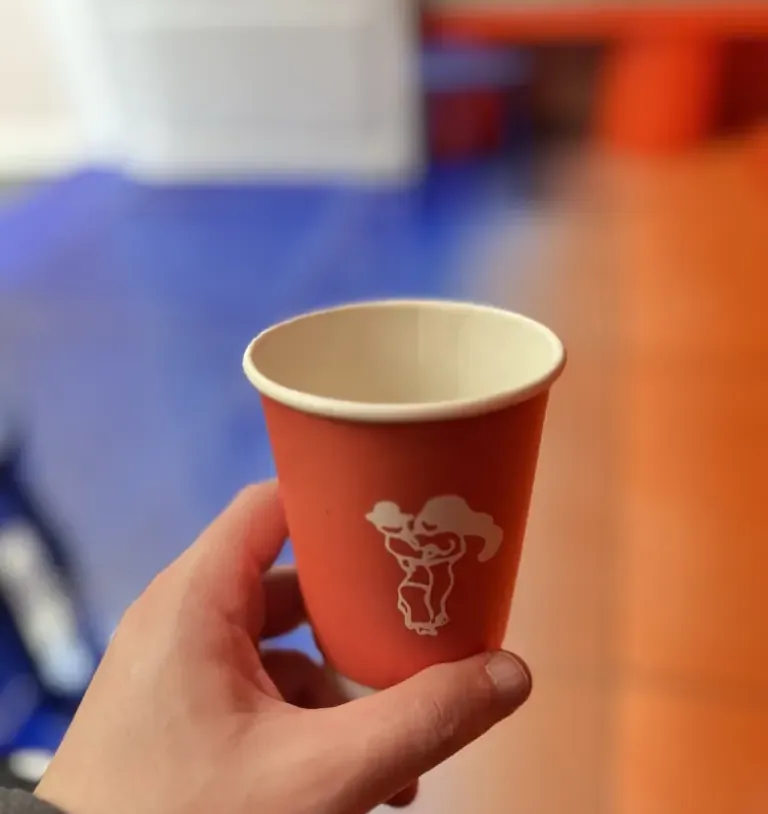 Copinho laranja de café na mão do Leo