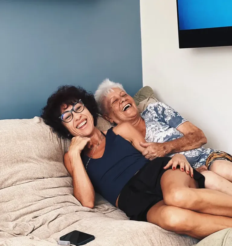 Duas mulheres da família rindo juntas no sofá