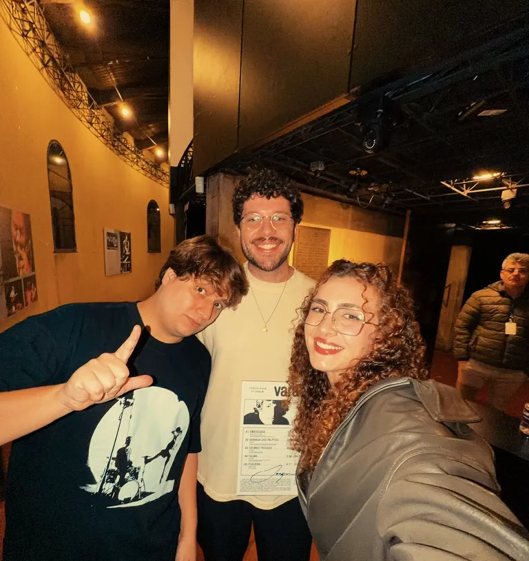 Leo segurando um encarte autografado, com amigos, depois de um show